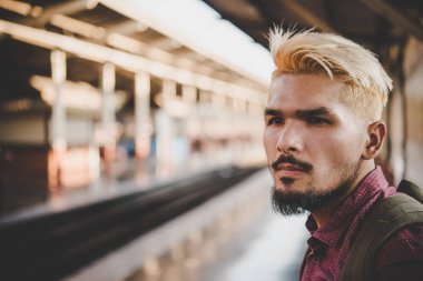 Tren istasyonu yürüyen genç hipster adam. Tren platformu için bekleyen adam. Seyahat kavramı.