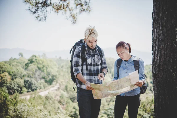 Young adventure couple discussing while looking at map during hiking in the mountain.