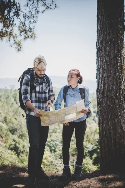 Young adventure couple discussing while looking at map during hiking in the mountain.
