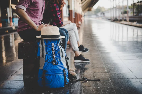年轻的时髦情侣坐在火车站的木凳上 坐在站台上等火车的情侣 — 图库照片