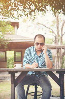 Genç işadamı ev bahçesinde çalışırken Smartphone kullanarak.