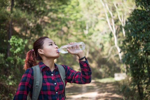 Happy woman tourist with backpack drinking water in nature.