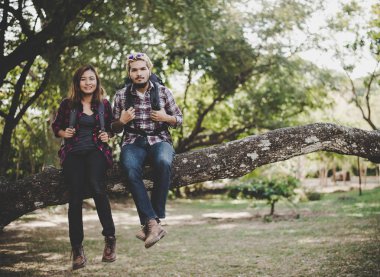 Genç yürüyüşçü Çift Dal üzerinde oturup dinlenmek doğa ile keyfini çıkarın. Seyahat kavramı.