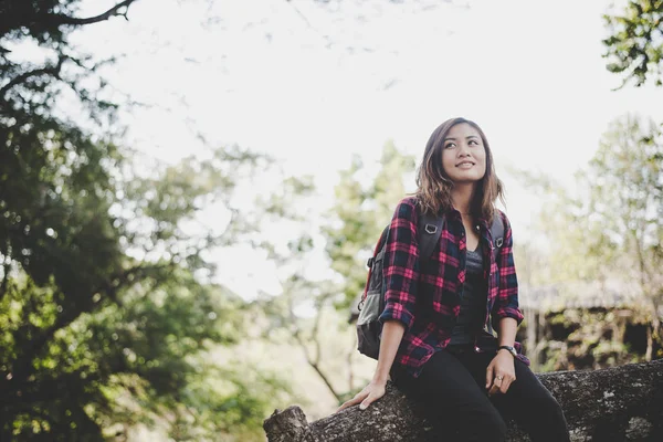 Young hiker woman sitting on branch with backpack, Travel concept.