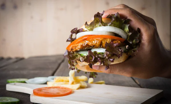 man holds burger with hands and potato chip.