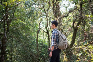 Genç hipster adam uzun yürüyüşe çıkan kimse almak biraz dinlenme vahşi dağ orman manzara zevk yürüyüş sırasında.
