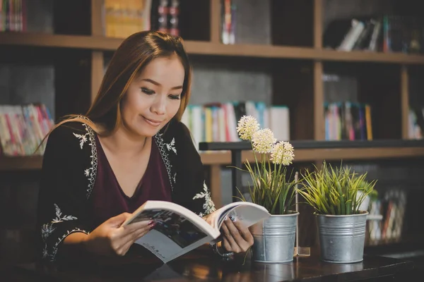 Happy business woman reading book while relaxing at cafe.