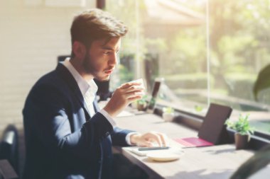 Takım elbise ve dizüstü kafede kapalı kullanma genç iş adamı. İş kavramı. Kahve molası sırasında içme.