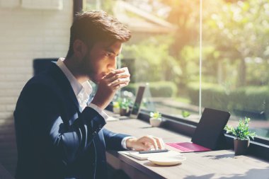 Takım elbise ve dizüstü kafede kapalı kullanma genç iş adamı. İş kavramı. Kahve molası sırasında içme.