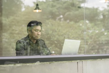 Onun laptopunda ofiste çalışan genç işadamı görüntüsü. 