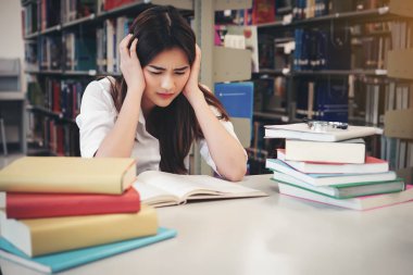 Üniversite kitaplığında kitap okurken kafa dokunmadan öğrenci portresi. Eğitim kavramı