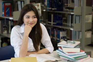 Fotoğraf gülümseyen genç oldukça Asya öğrenci Kitaplığı'nda okuyordu. Eğitim kavramı.
