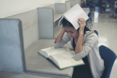 Öğrenci kitap okuma kitap kolej kütüphane içinde iken kapak kafayla portresi. Eğitim kavramı