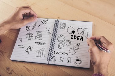 İşadamı el üstünde defter iş doodle kutsal kişilerin resmi ile yazma kapatın. İş kavramı.