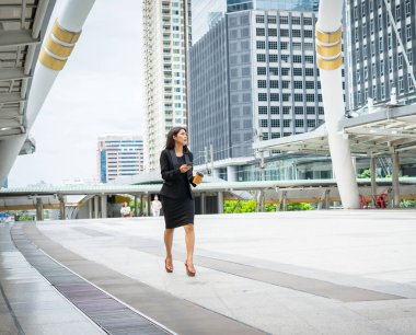 El ile office binalarda adam sokakta yürürken kahvesiyle telefonuyla iş kadını