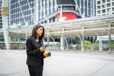 El ile office binalarda adam sokakta yürürken kahvesiyle telefonuyla iş kadını