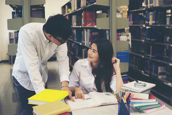 一緒に本を読んで図書館に学生の若いアジアのカップル 教育コンセプト — ストック写真