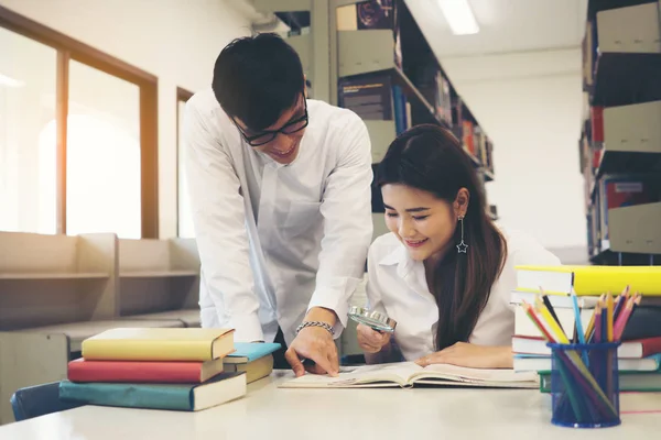一緒に本を読んで図書館に学生の若いアジアのカップル 教育コンセプト — ストック写真