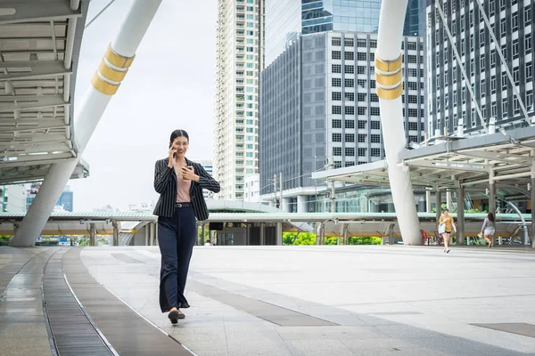 Cep telefonu hakkını izle sokakta seyir ofis binaları içinde belgili tanımlık geçmiş ile konuşurken yürüyüş iş kadını