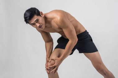 Genç adam elleriyle diz bağ yaralanması üzerine beyaz izole acı sonra acı içinde tutan kuvvetli atletik bacakları ile spor.