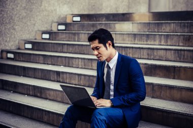 Laptop ile çalışma merdiven üzerinde oturan hayal kırıklığına uğramış genç adam. Çalışmaları ile mutsuz ilgili sorun.