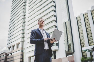 Yakışıklı işadamı ofis dizüstü bilgisayar ile giderken elinde duran.