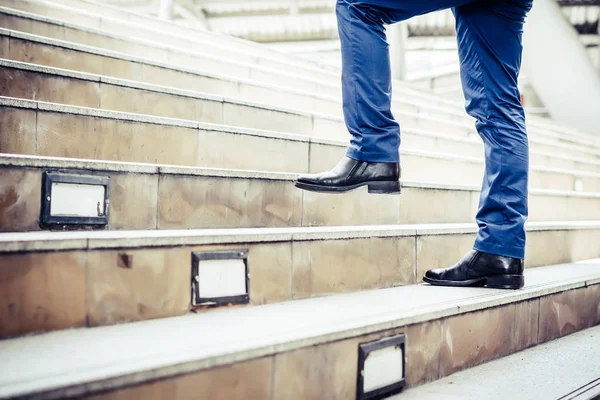 Close up of young businessman walking upstairs outside office.