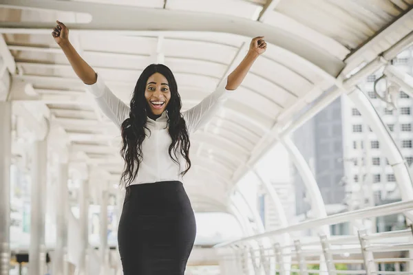 Young business woman achieve goal, raised hands