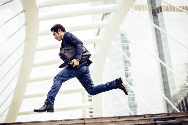 Young businessman with a briefcase running in a city street hurry up to go work.