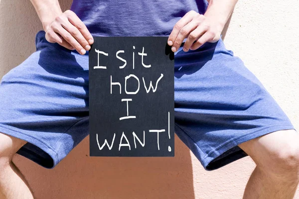 Мужчина держит плакат с надписью "Я сижу, как хочу " — стоковое фото