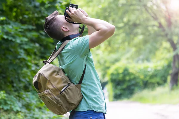 En ung man tar bilder av naturen i skogen — Stockfoto