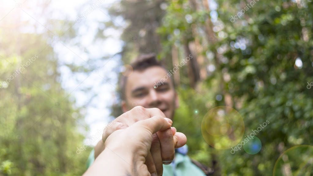 The young man pulls the girl's hand on the forest path