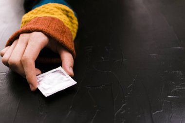 Adam prezervatif için ulaşır. Siyah arka plan, contraceptie gün kavramı