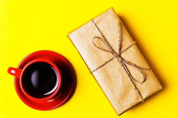 Taza Roja con café y regalo sobre fondo amarillo — Foto de Stock