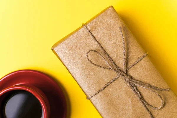 Taza Roja con café y regalo sobre fondo amarillo — Foto de Stock