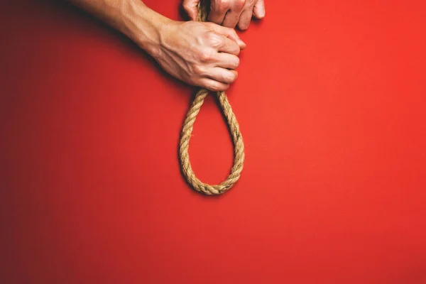 Man tying a knot of rope on a red background — Stock Photo, Image