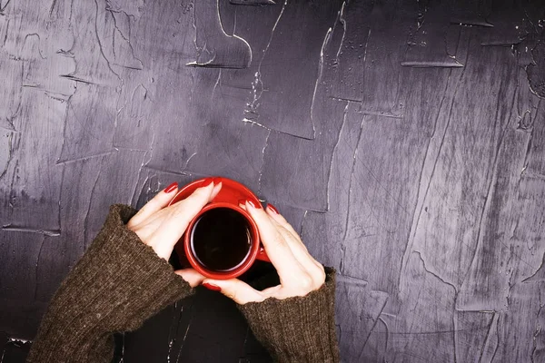 Kırmızı fincan kahve koyu arka plan üzerinde tutan kız