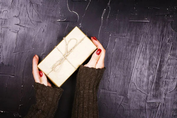 Bir hediye karanlık bir arka planda tutan kız.