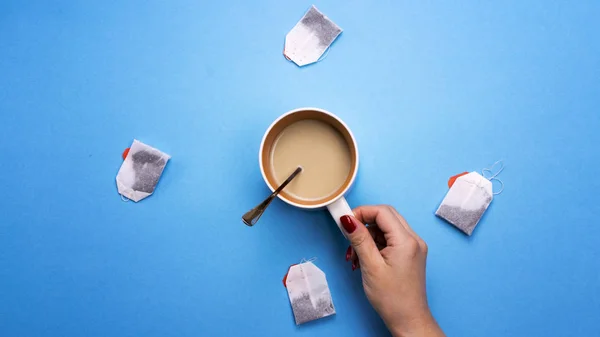 Girl holding a Cup of coffee surrounded by tea bags. The concept of beverages and preferences. Coffee pause, a break.