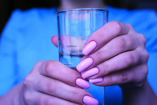 Bir hemşire bir bardak su tutan genç bir kız giyinmiş.