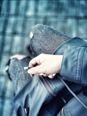 Kız akşamleyin bankta oturur. Mobil fotoğraf