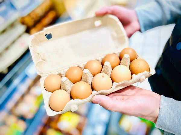 Ellerinde tavuk yumurtası seti var. Süpermarket. Mobil fotoğraf.