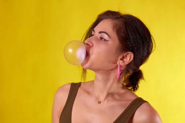 Menina bonita em um fundo amarelo no estúdio infla che — Fotografia de Stock