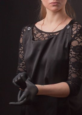 Siyah elbiseli bir kadın, eldivenli, karanlık bir arka planda poz veriyor, elleriyle poz veriyor..