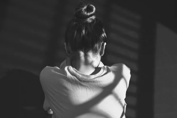 Foto de uma menina sentada no chão em um quarto escuro fechado . — Fotografia de Stock