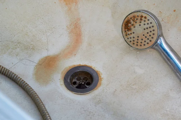 Kirli, paslı bir banyo, banyoda, en altta bir su bidonu var. Sağlıksız, eski tesisat..