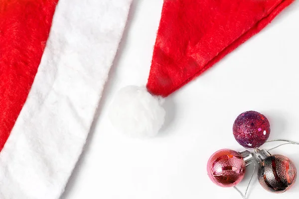 Красный шапочка Санта-Клауса лежит на белом фоне, вид сверху возле рождественских игрушек. Незаполненные для открыток. — стоковое фото