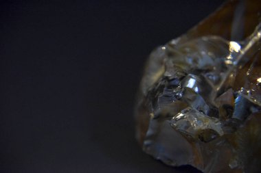 Koyu arkaplanda sarı volkanik cam kristal var.