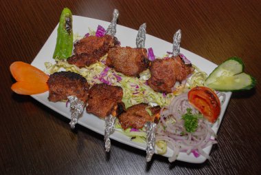 Beyaz tabakta salatalı kuzu pirzola.