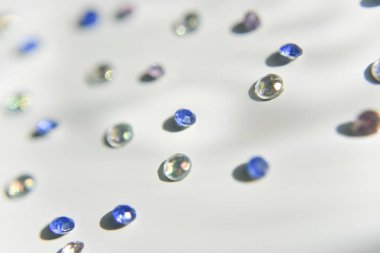 Beyaz arka planda farklı renklerde yapay elmaslar. El işi konsepti. Seçici odak.